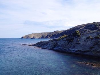 Scenic view of sea by mountains against sky