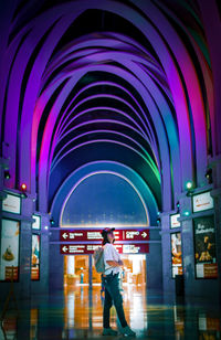 Rear view of man standing against illuminated lights at night