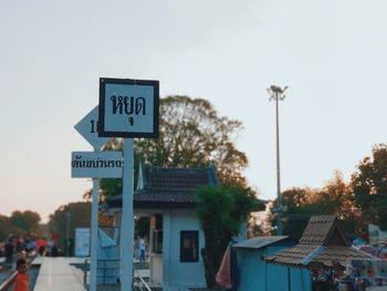 Road sign by building against sky