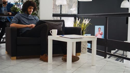 Rear view of woman using mobile phone while sitting on chairs