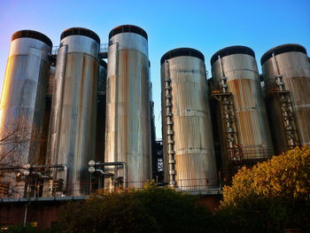 Low angle view of industry against clear blue sky