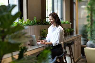 Young woman using phone while sitting on table