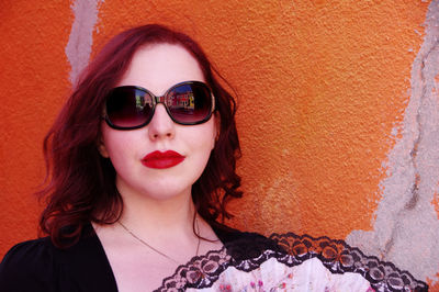 Beautiful woman wearing sunglasses against wall