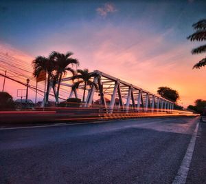 Bridge over road against sky at sunset