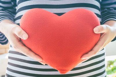 Midsection of woman holding heart shape with hands