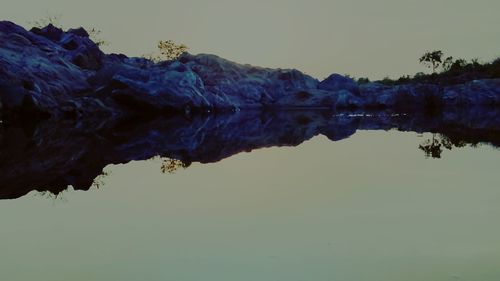 Reflection of tree in lake against sky