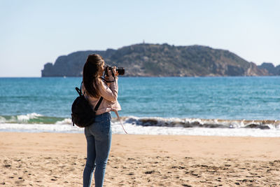 Woman photographing sea at beach