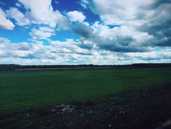 Scenic view of grassy field against cloudy sky