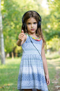 Smiling girl listening music while standing at park