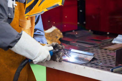 Midsection of male welder welding metal in factory