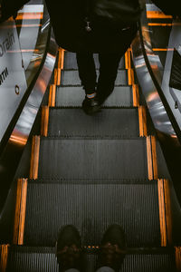 Low section of man standing on escalator