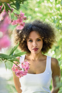 Portrait of beautiful young woman standing by plants