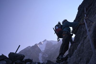 Low angle view of person on rock against sky