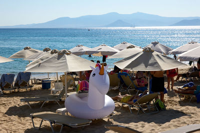 Deck chairs and parasols on beach against sky
