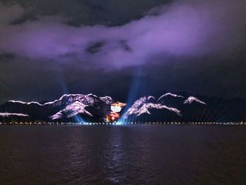 Scenic view of illuminated lake against sky at night