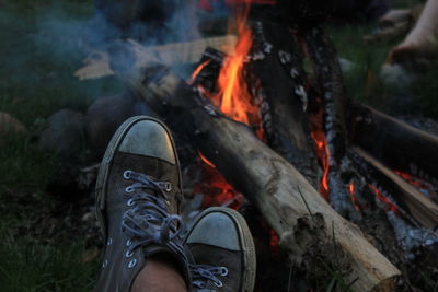 Human leg next to bonfire burning in backyard