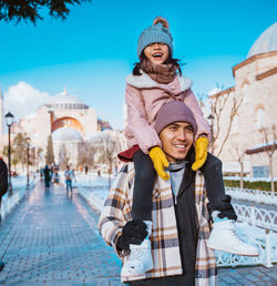 Portrait of smiling friends standing against city