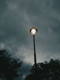 Low angle view of street light against dramatic sky