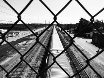 Train on railroad track seen through chainlink fence