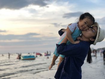 Smiling young woman playing with daughter at beach