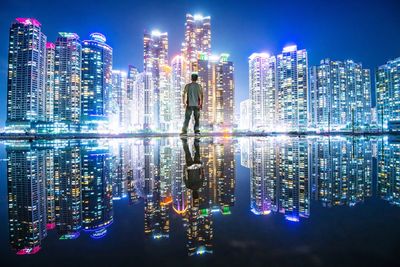 Digital composite image of illuminated modern buildings in city at night