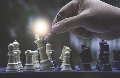 Cropped hand of person playing chess outdoors