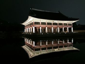 Illuminated building by lake at night