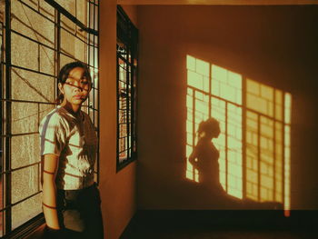 Side view of woman looking through window at home