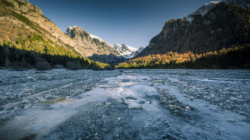 Scenic view of river by mountains against clear sky