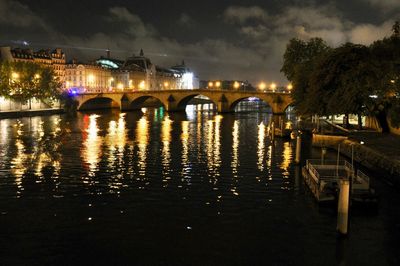 Illuminated bridge over river in city at night