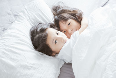 High angle portrait of siblings lying on bed