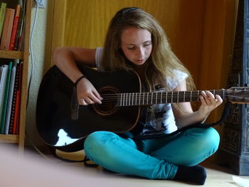 Portrait of young woman playing guitar