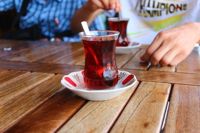 Midsection of person holding drink on table