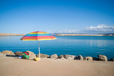 People at beach against clear blue sky