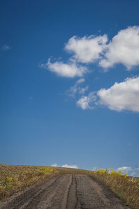 Surface level of road amidst field against sky