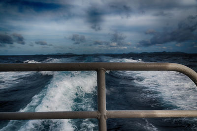 Scenic view of sea seen through railing of boat against sky 