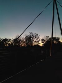 Silhouette trees against clear sky at sunset