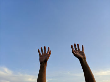 Cropped hands of person against sky