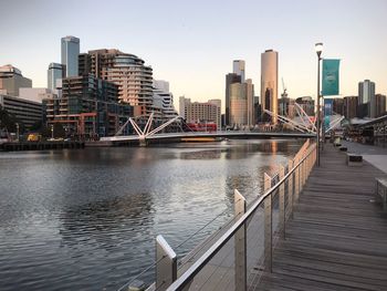 Bridge over river by buildings in city against sky