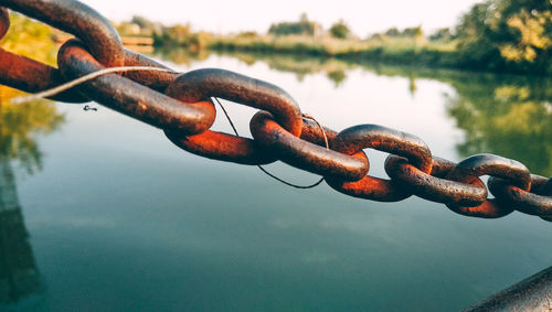Close-up of rusty chain on lake