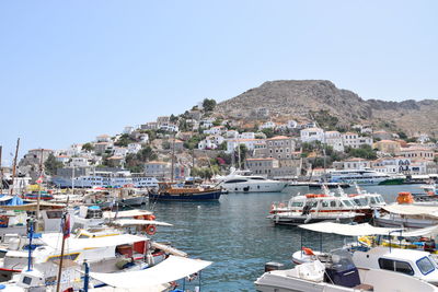 Sailboats moored in harbor by city against clear sky