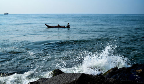 People in sea against clear sky