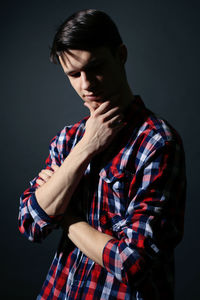 Thoughtful young man standing against gray background