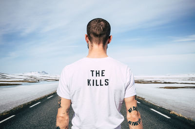 Rear view of man standing on road against sky