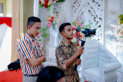 Man looking at friend filming in wedding ceremony