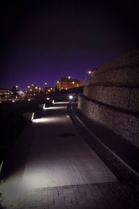 Illuminated city street against sky at night