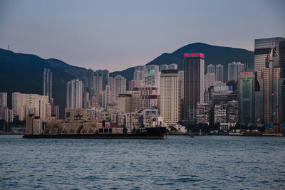 Sea by city buildings against clear sky