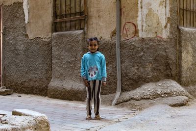 Portrait of boy standing against building