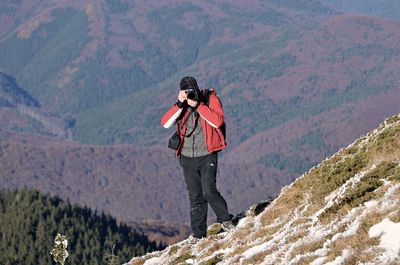 Man with umbrella on mountain range against sky