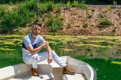 Portrait of young man sitting by lake